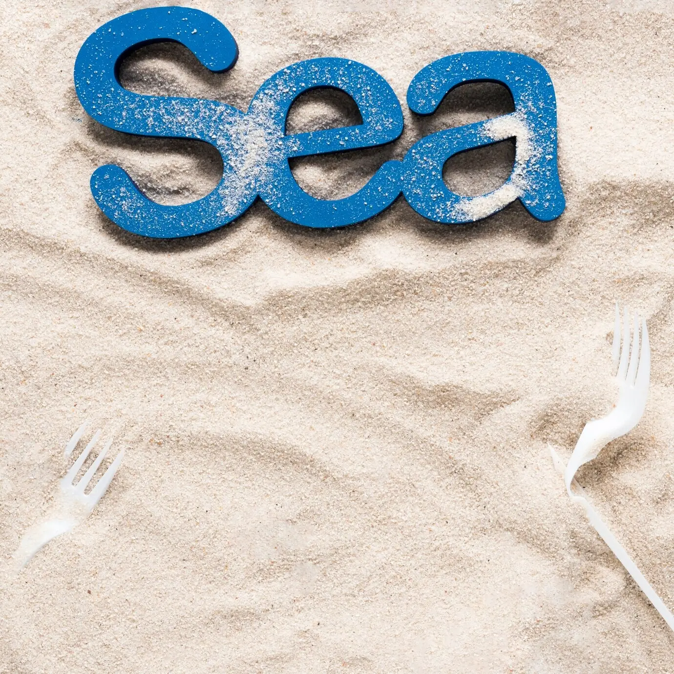 Draufsicht auf das Meer am Strand mit Plastikgabeln